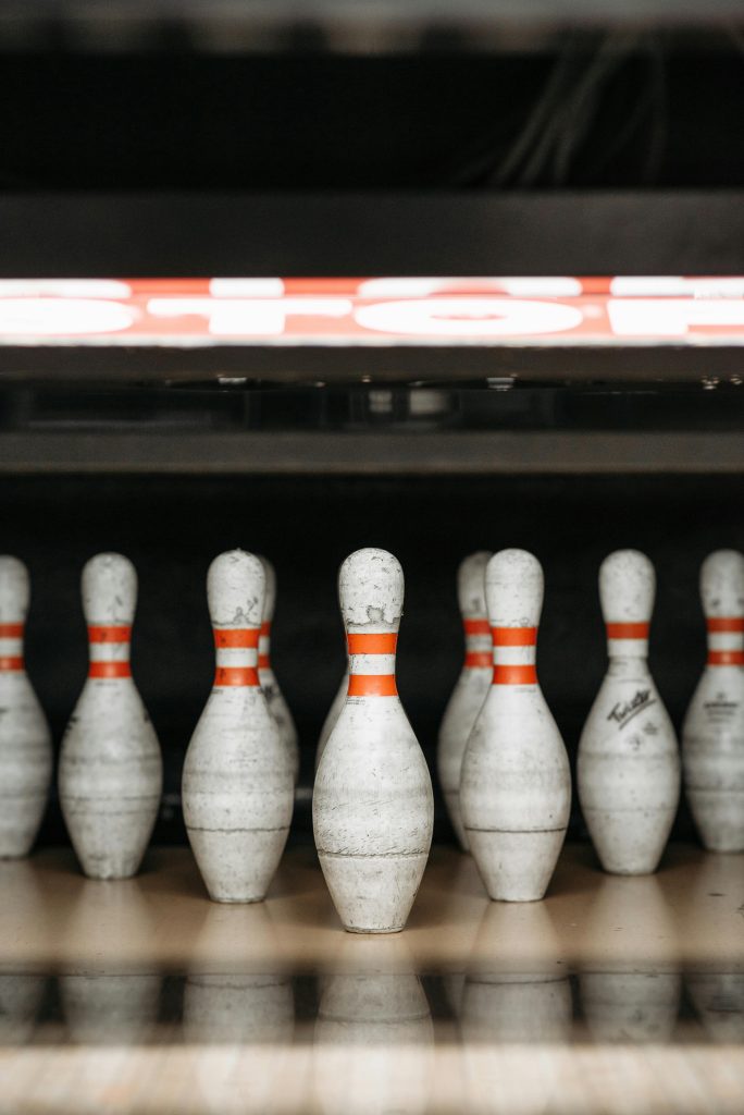 A row of bowling pins ready for a game on the alley floor indoors.